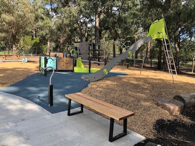 Climbing equipment and a bench beside rubber and mulched play surfacing